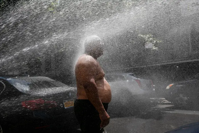 Rey Gomez cools off in the spray from a fire hydrant, in New York. The city has opened more than 300 fire hydrants with sprinkler caps to help residents cool off during a heat wave.
